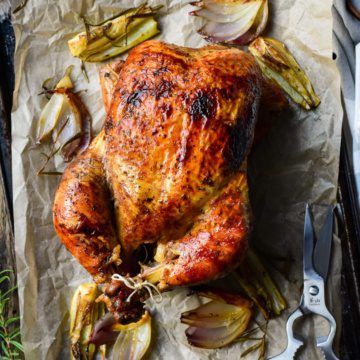 A whole chicken trussed on sheet pan with chicken sheers.