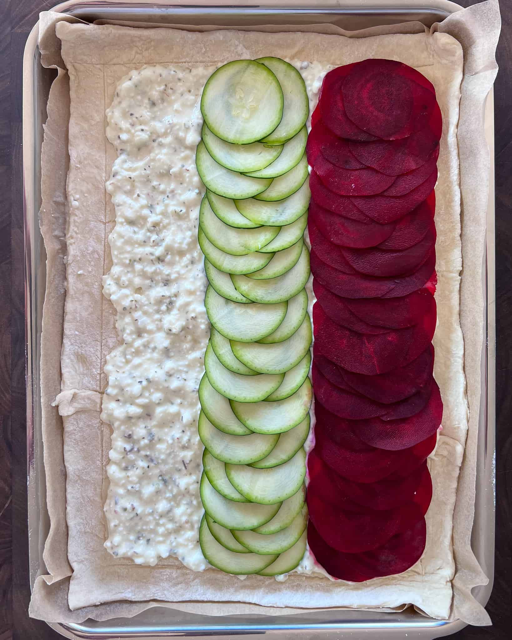A row of zucchini and beets laid over the cheese layer on the puff pastry.