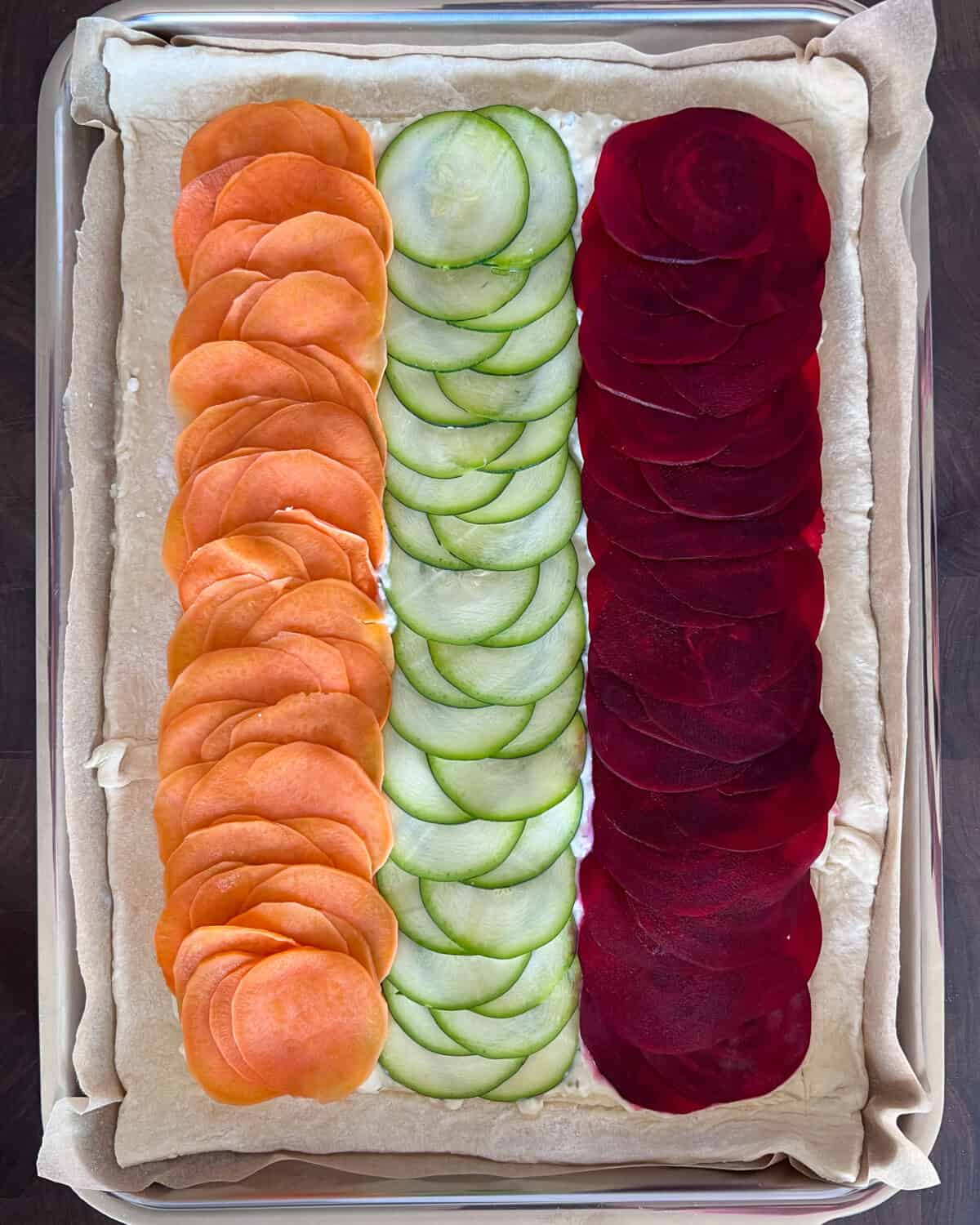 A row of zucchini, beets and sweet potatoes layered over the cheese layer on the puff pastry.
