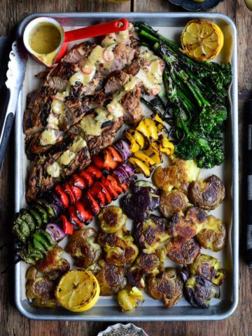 A colourful plater of Spicy Maple Pork Tenderloins, skewered vegetables, smashed potatoes and broccolini.