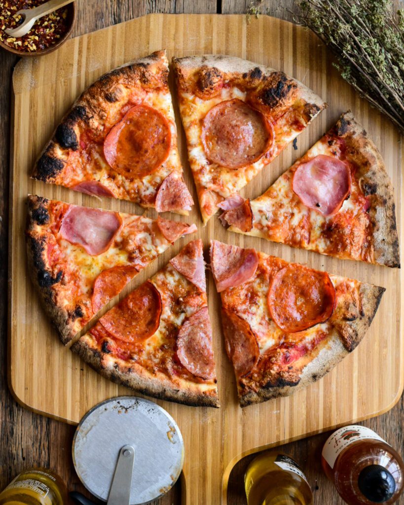 A pizza with salami, pepperoni, and ham, sliced in six pieces.