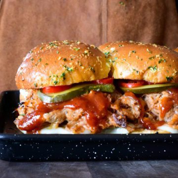 A side view of pulled pork sliders with BBQ sauce.