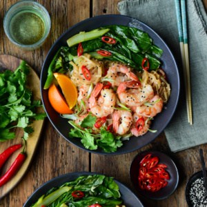 A sous vide shrimp noodle bowl with cilantro, orange wedges and Chinese broccoli.