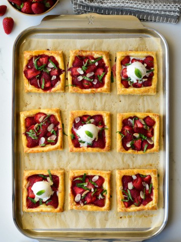 Nine Puff Pastry Strawberry Tarts on a sheet pan, served with a scoop of ice cream on three.