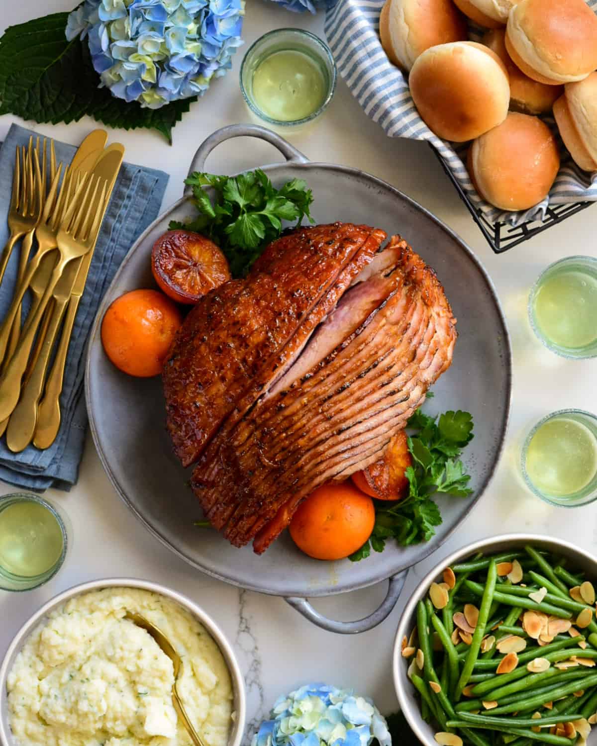 A glossy, sliced Minneola glazed Spiral Ham served with mashed potatoes, green beans and bread.