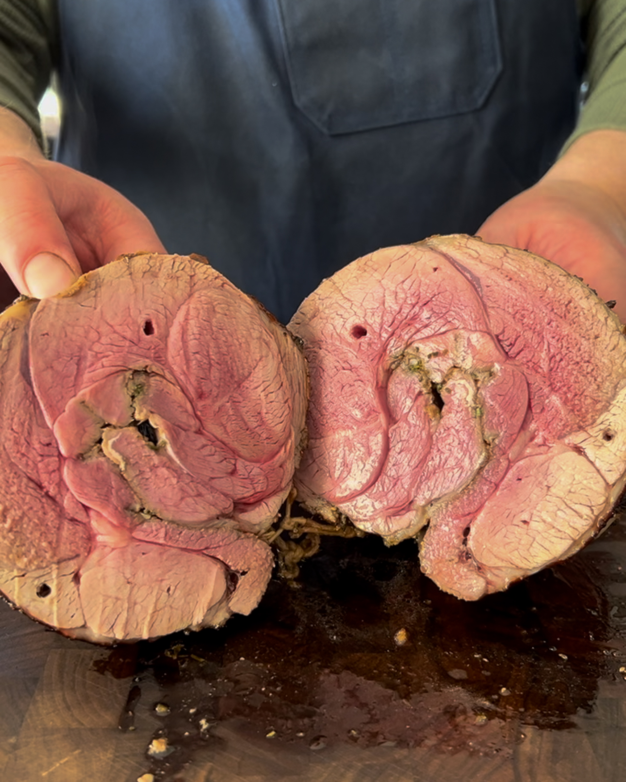A sliced open leg of lamb roast revealing the blush center.