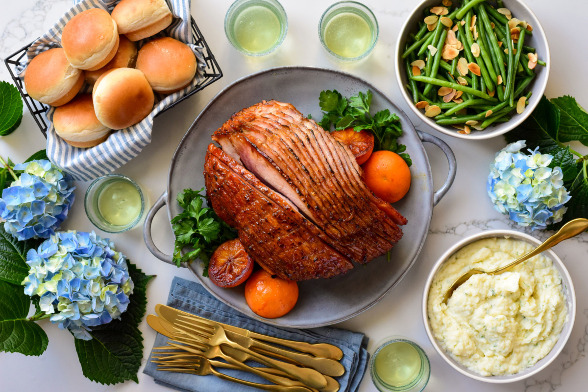 An Easter ham with an orange glaze and served with beans, mashed potatoes and buns.