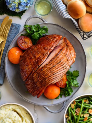 A glossy, sliced Minneola glazed Spiral Ham served with mashed potatoes, green beans and bread.