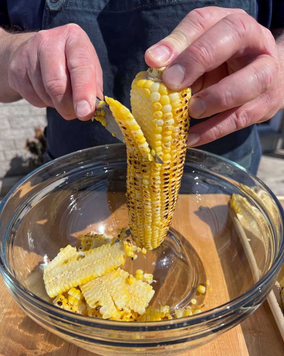 Stand each ear of corn on a smaller bowl (that is upside down) within a large bowl. Using a sharp knife, cut down along the cob to strip off the kernels.