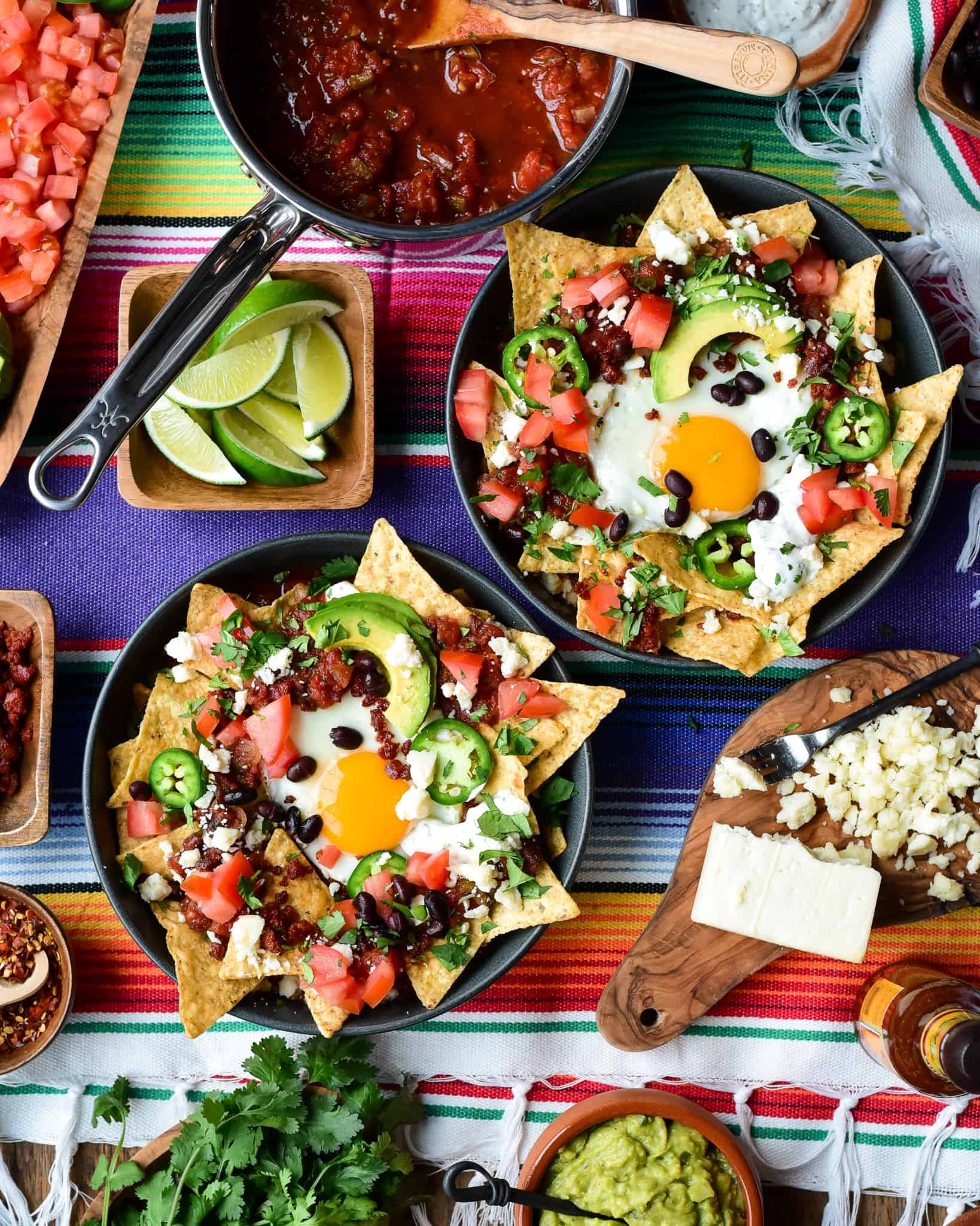Twp chilaquiles breakfast bowls with a sunny side up egg and other colourful toppings. 