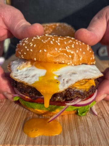 A double smash burger with a fried egg with yolk running down the burger.
