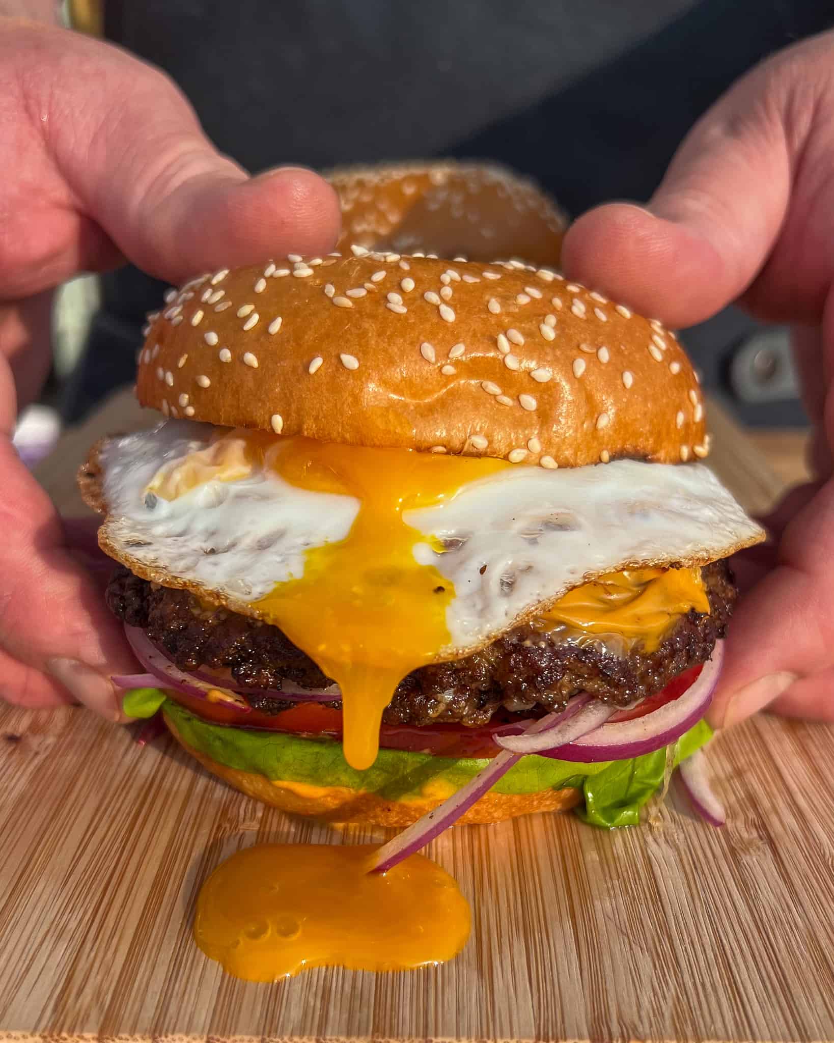 A double smash burger with a fried egg with yolk running down the burger. 