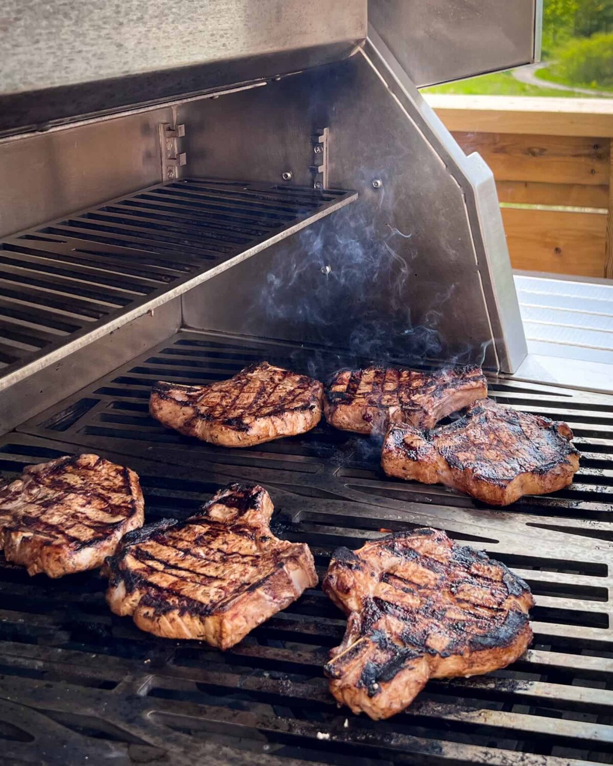 Six pork chops on the grill with beautiful grill marks.