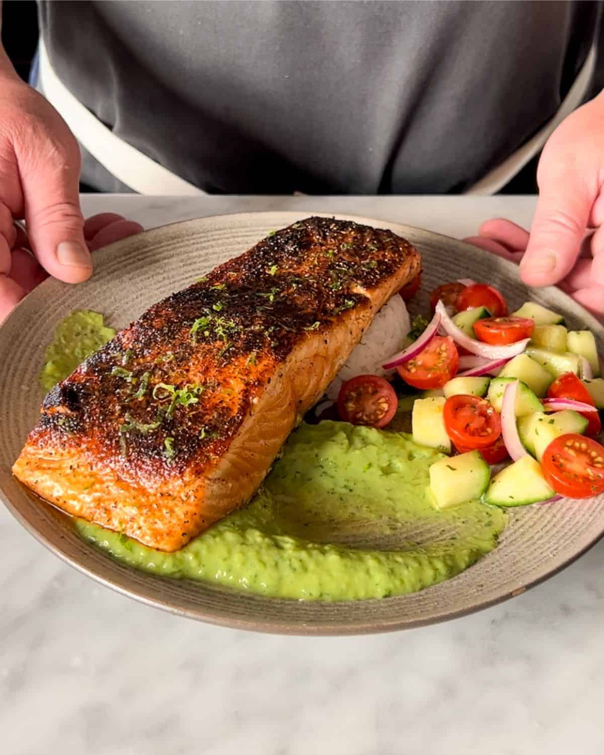 Pan seared blackened salmon served with charred jalapeno crema, salad and rice.