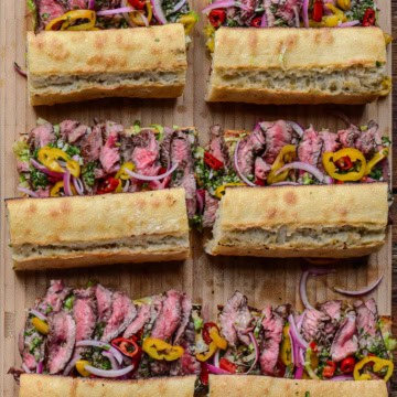 Six grilled steak sandwiches on baguettes.