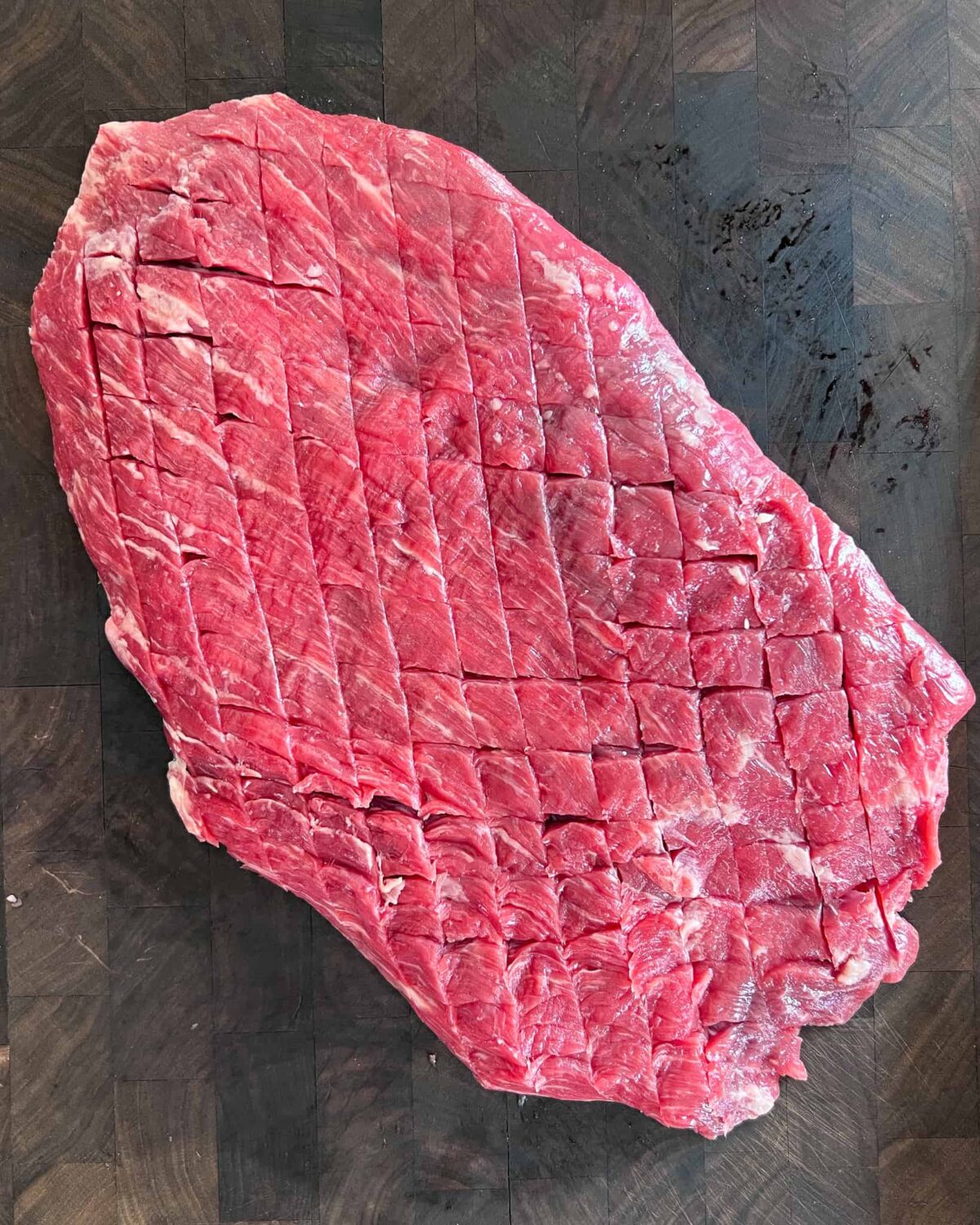 A flank steak crosshatched with diagonal slices.