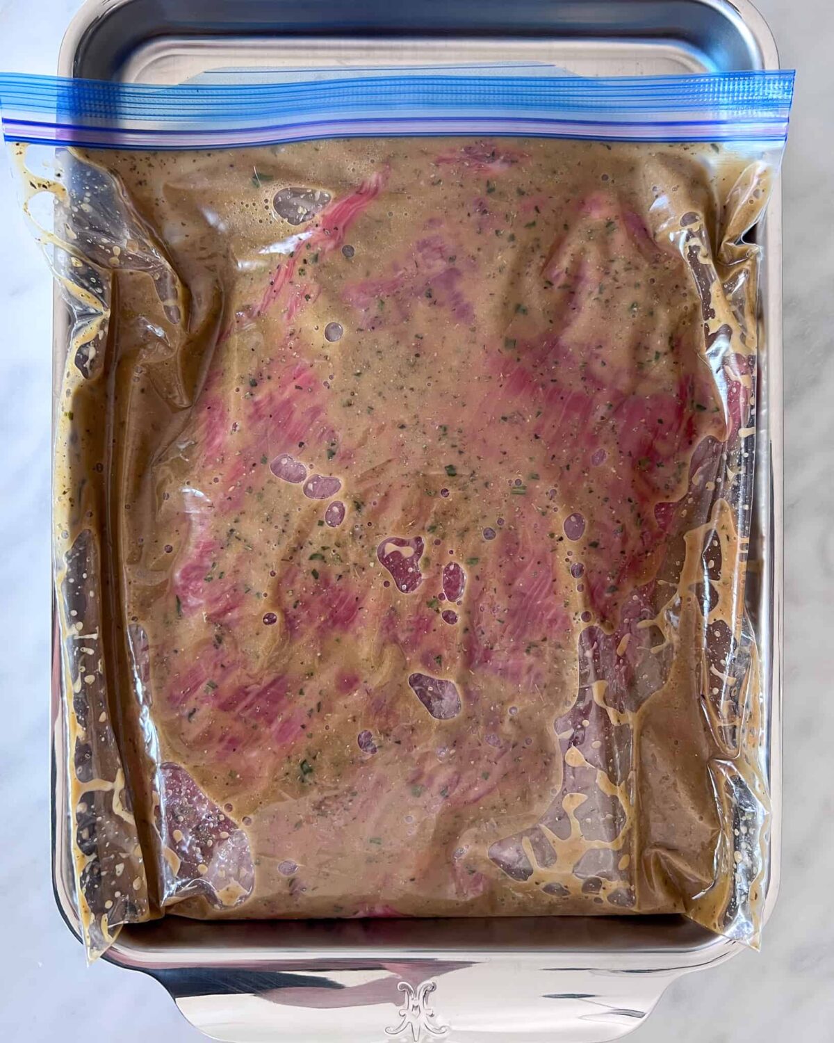 A flank steak marinating in a sealed bag.
