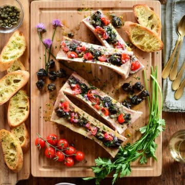 Four Bone Marrow bones with Garlic Butter Escargot, Tomatoes and Chive Flowers.