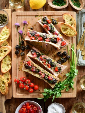 Four Bone Marrow bones with Garlic Butter Escargot, Tomatoes and Chive Flowers.