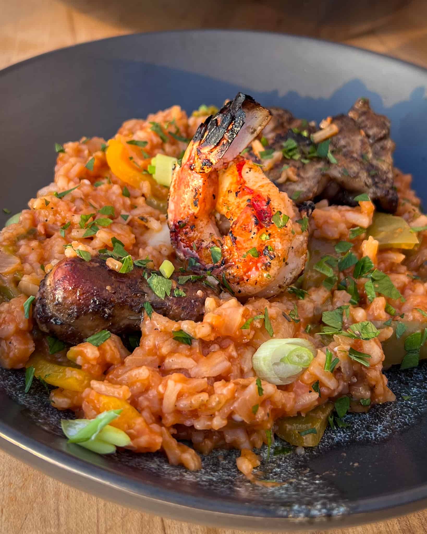 A bowl of grilled jambalaya with grilled shrimp, chicken and sausage.