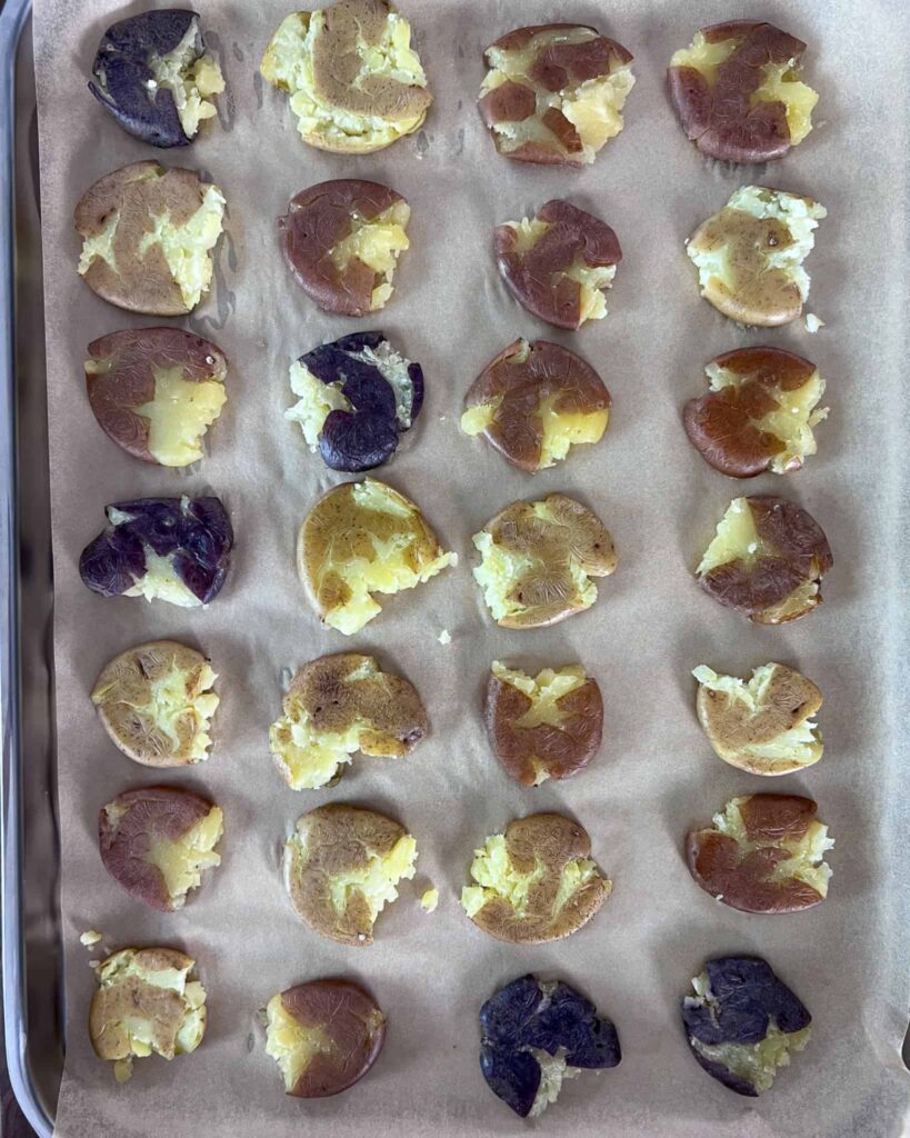 A parchment lined sheet pan with four rows of smashed pototoes.