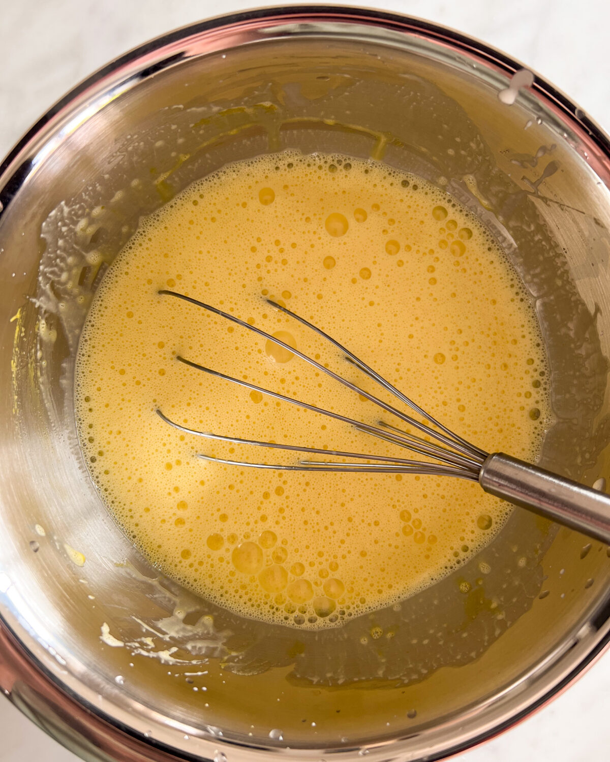 Slowly mix the warm cream mixture into the eggs. 