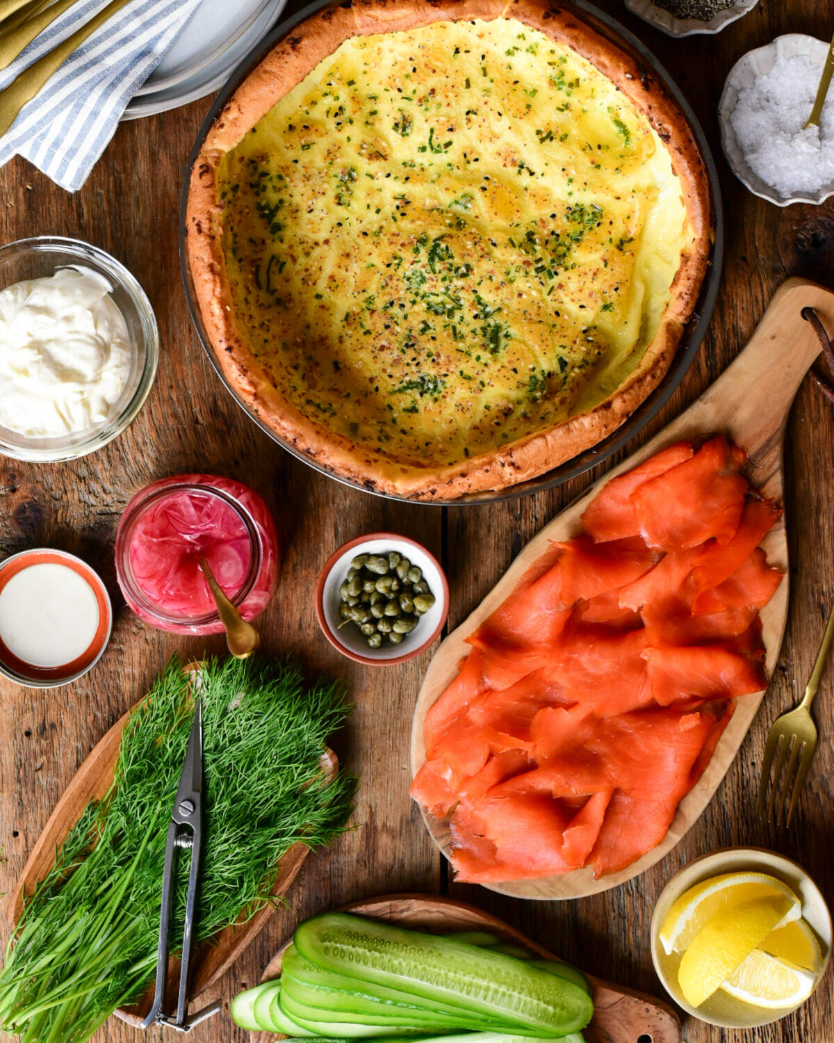 A baked Dutch baby about to get loaded with smoked salmon, cream cheese, onions, capers and dill.