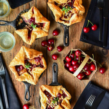 Four savoury cherry puff pastry tarts in mini cast iron skillets.
