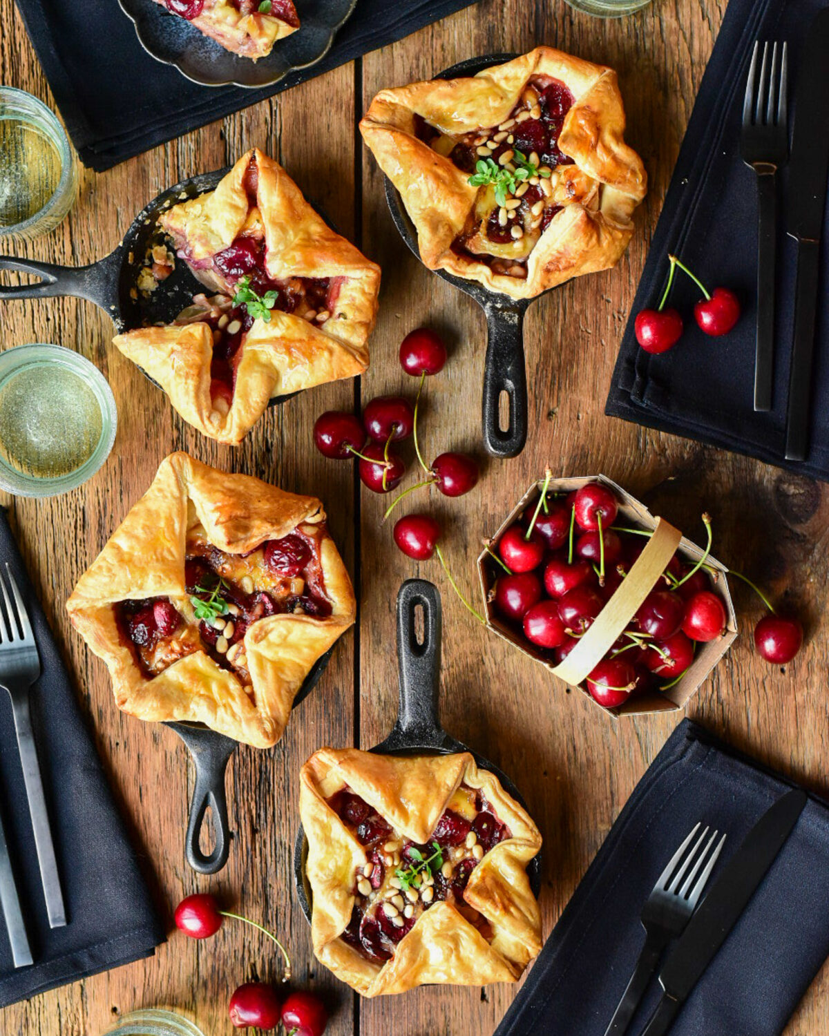 Four savoury cherry puff pastry tarts in mini cast iron skillets.