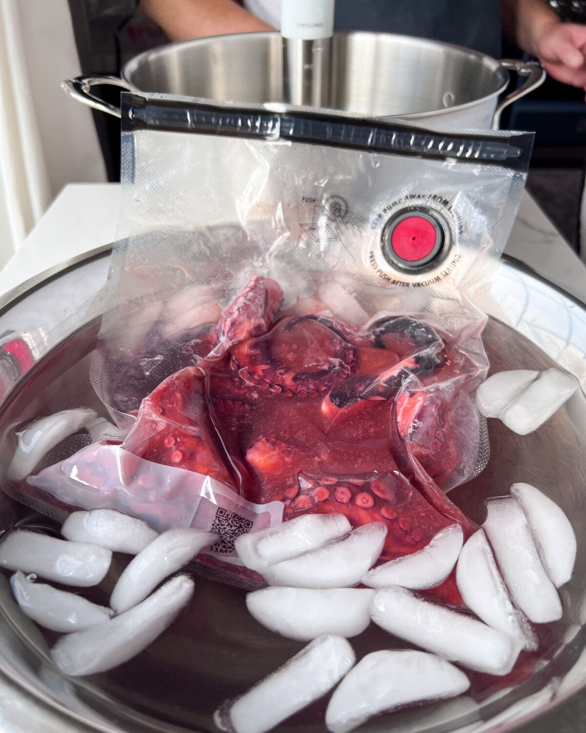 When the octopus has finished cooking in the sous-vide bath, carefully remove the bag, and place it into a large bowl of ice water to stop the cooking process.