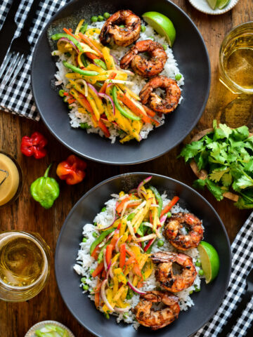 Two bowls of jerk shrimp and rice with a peach-mango slaw.