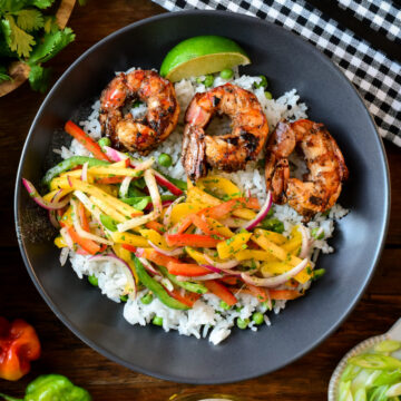 A bowl of jerk shrimp with rice and slaw.