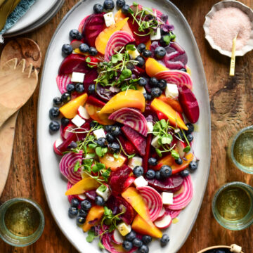 A platter of a sous-vide beet salad with three varieties of beets, radishes, blueberries, micro greens and feta cheese. Served with wine, extra micro greens and blueberries.