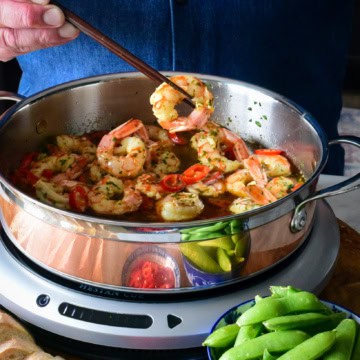 Lifting a shrimp sautéed in garlic in a copper pan.