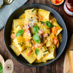 A bowl of blistered tomato pasta served with grated Parmesan and fresh basil.