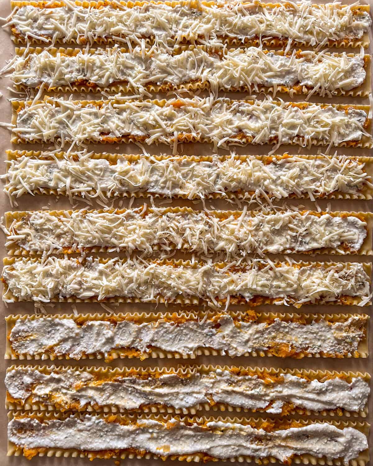 Béchamel sauce and shredded mozzarella spread over lasagna noodles.