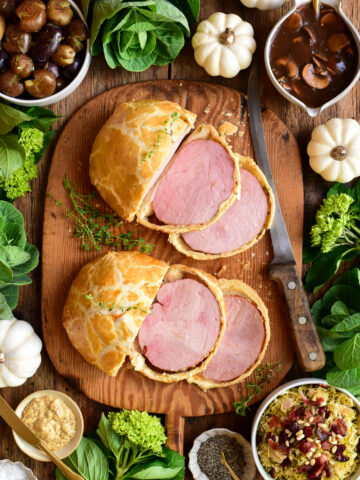 Two sliced ham wellingtons served with Marsala Mushroom Sauce, Shredded Brussels Sprouts with Pine Nuts and Pancetta, and smashed potatoes with thyme.