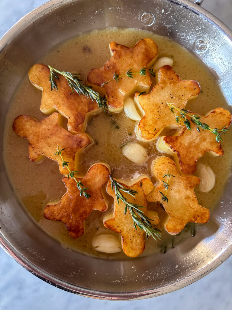 A skillet of golden brown gingerbread fondant potatoes in a pan.