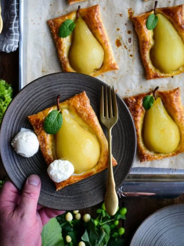 A poached pear baked in a crispy puff pastry shell and served with two scoops of ice cream.