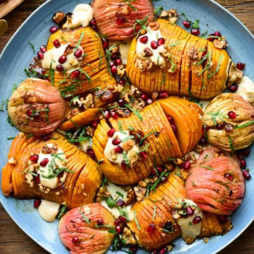 A platter of hasselback honeynut Squash and apples with a hummus dressing, pomegranate arils and chopped mint.