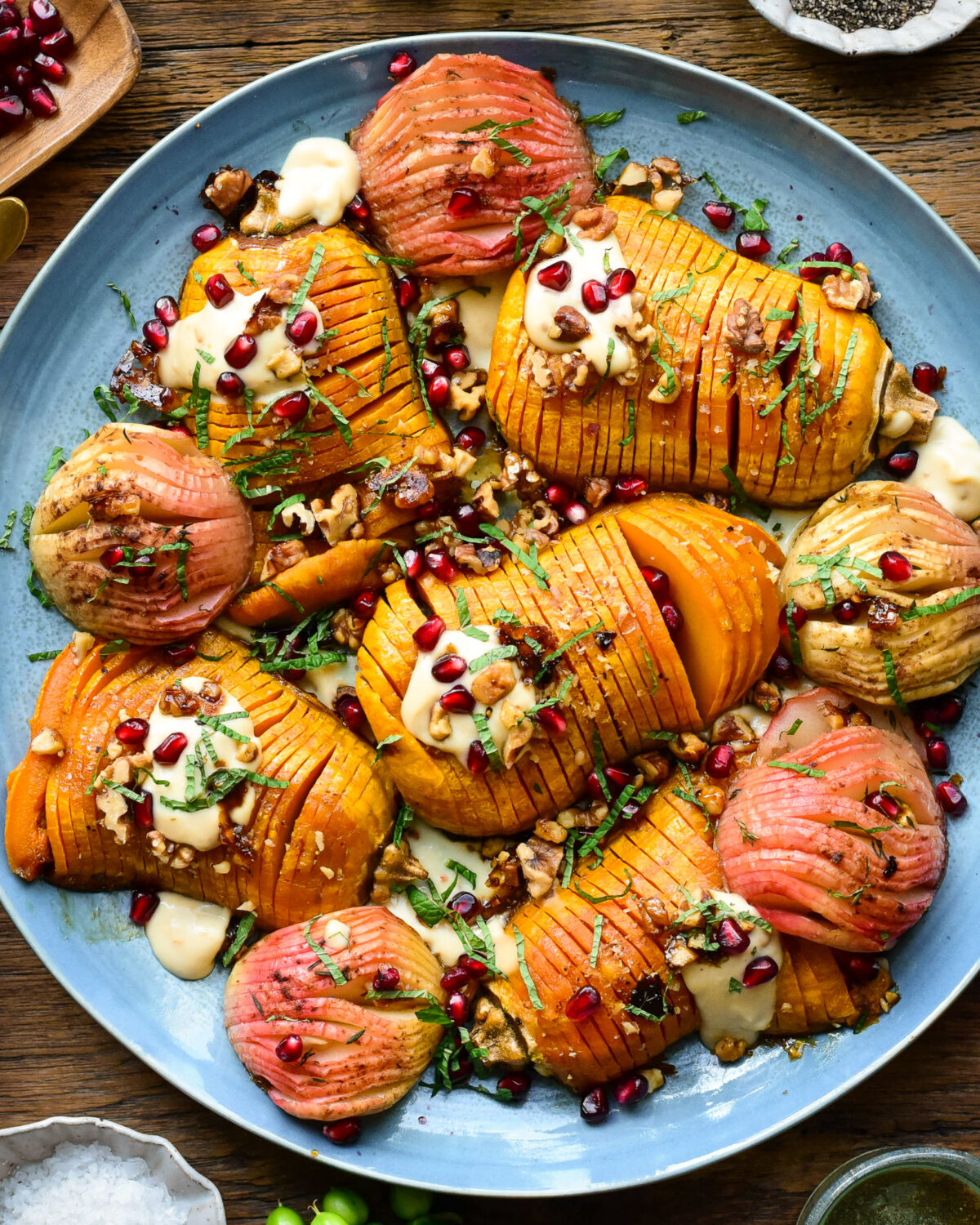 A platter of hasselback honeynut Squash and apples with a hummus dressing, pomegranate arils and chopped mint.