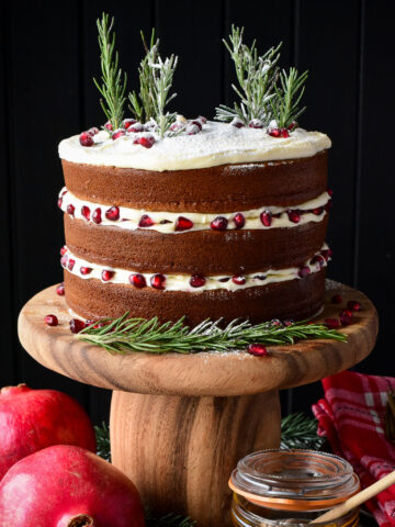 A three layer Honey Cake with Cream Cheese Frosting decorated with rosemary trees and pomegranate arils.