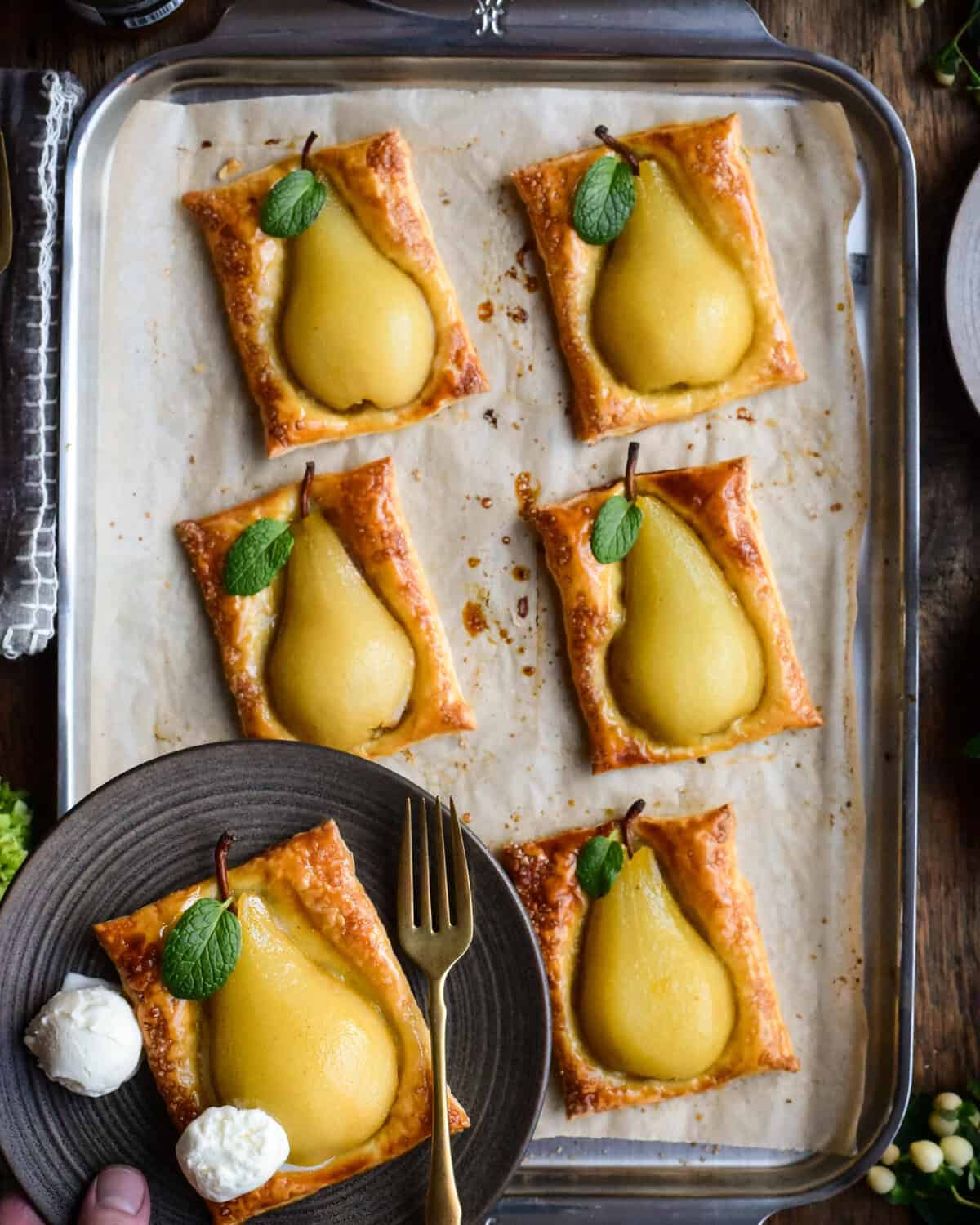 Six pear puff pastry desserts with a mint leaf.