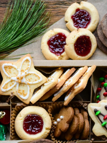Holiday thumbprint cookies with raspberry jam in a Christmas cookie box.