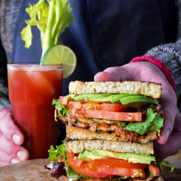 Two haves of a BBQ spicy chicken club sandwiched stacked together with a spicy Caesar cocktail.
