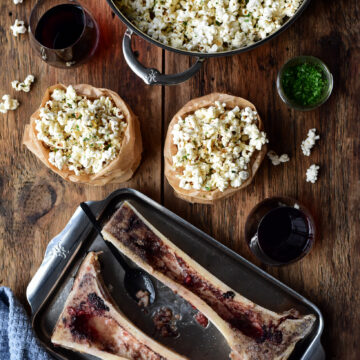 A pot and two bags of roasted bone marrow with garlic butter popcorn. Two roasted canoe bones with the bone marrow scraped out.