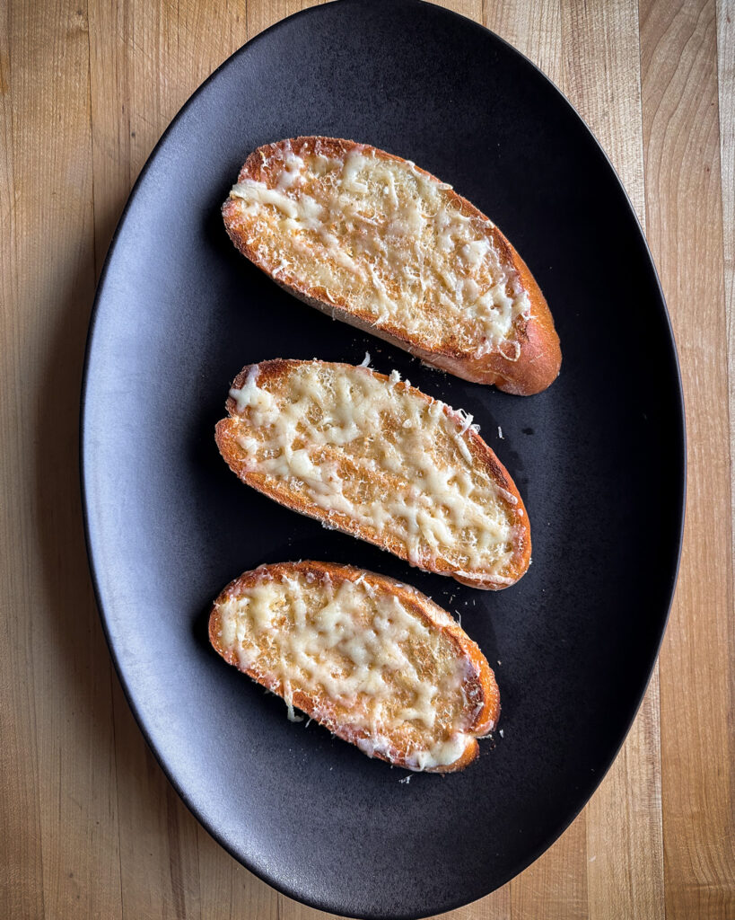 Three slices of toast (cheese side up) on a platter.