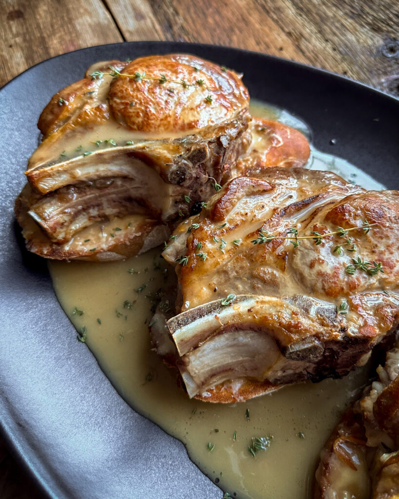 Thick cut and stuffed pork chops are placed on the toast and gravy is poured overtop.