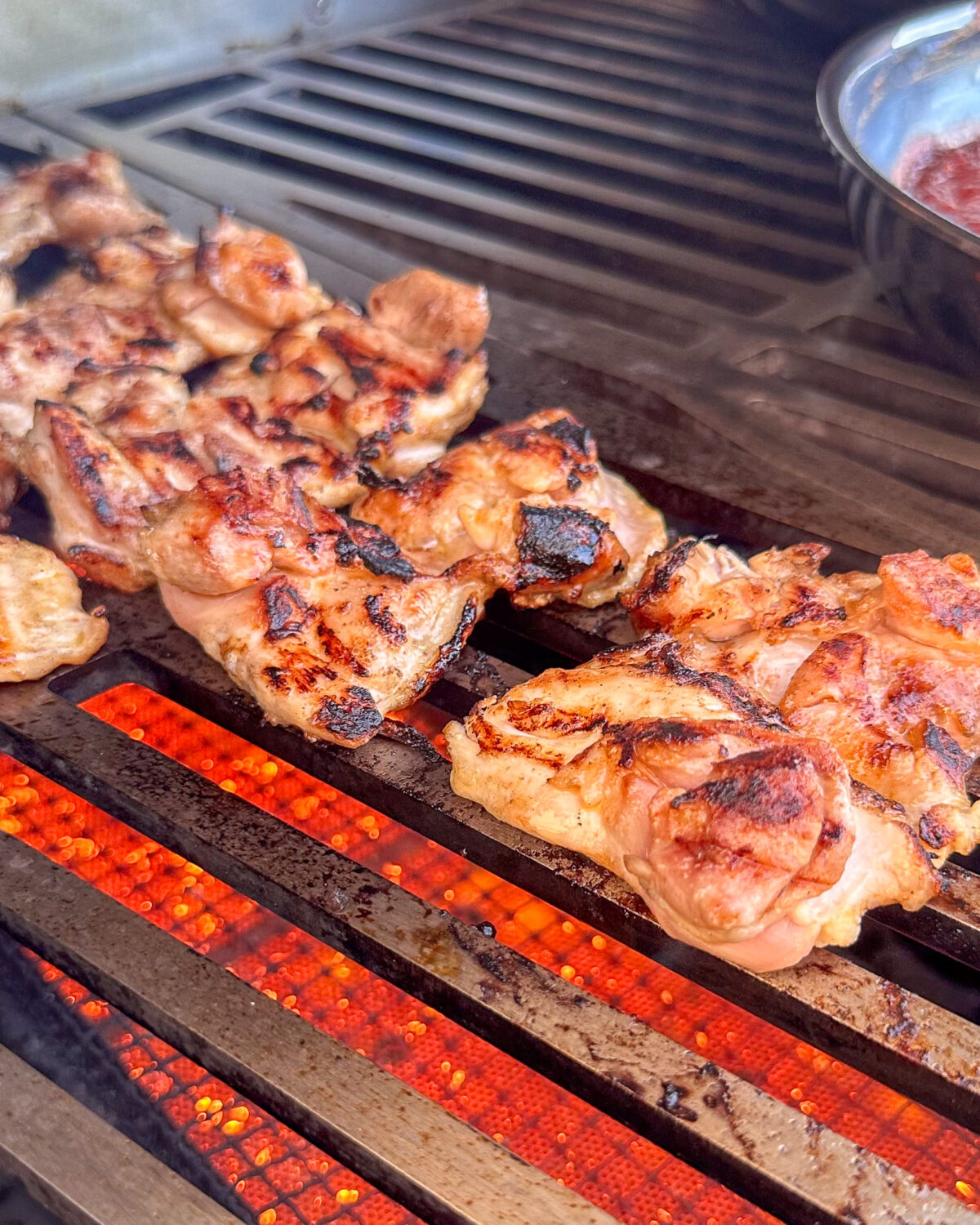 Grill chicken thighs until lightly charred on both sides and the internal temperature reaches 165°F or more.