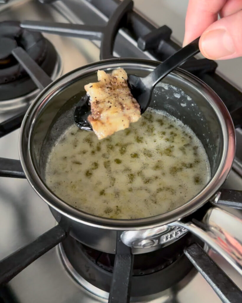 Adding a scoop of marrow to a pan of garlic butter.